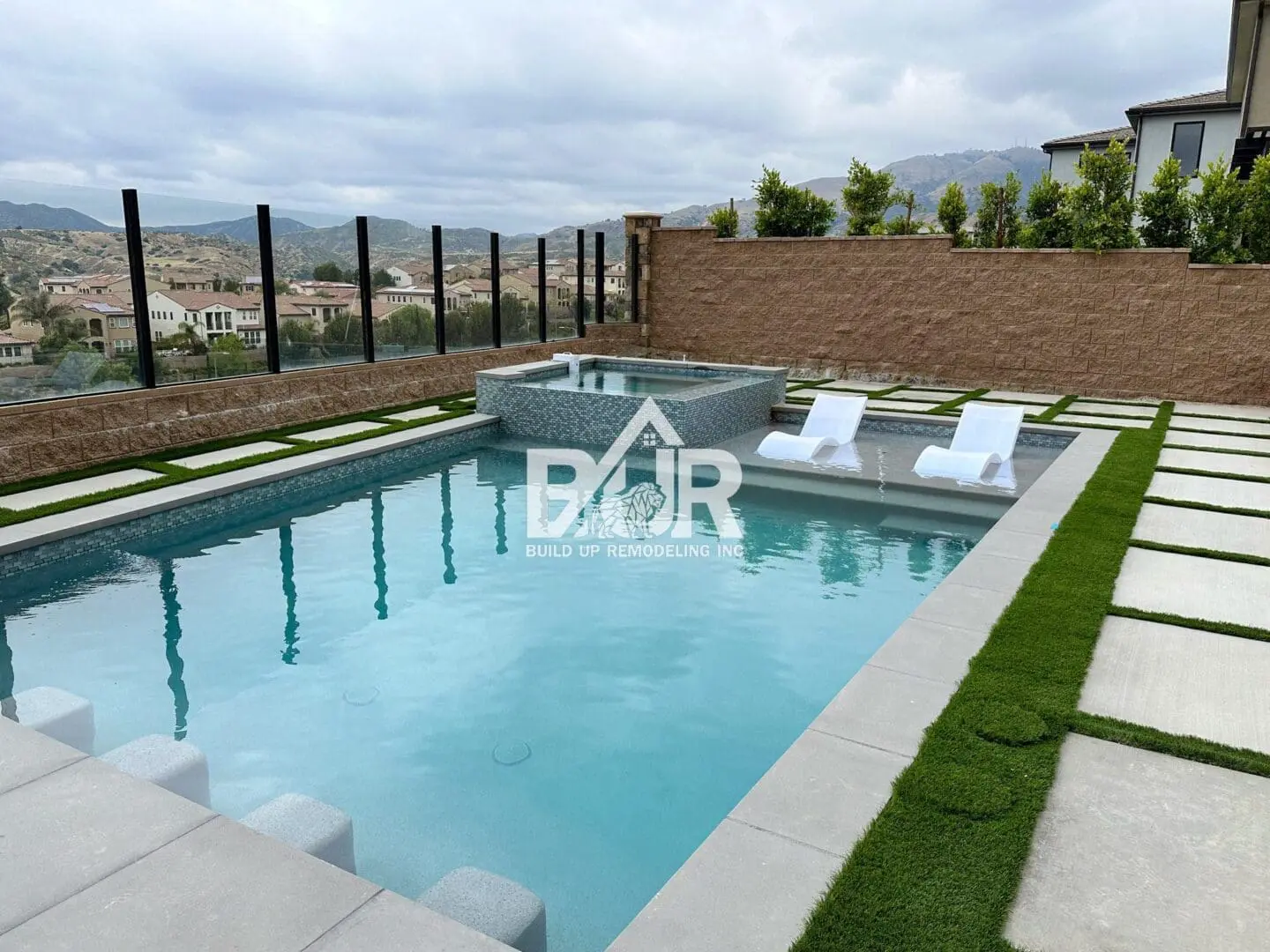 Modern outdoor pool with lounge chairs and scenic hill views.