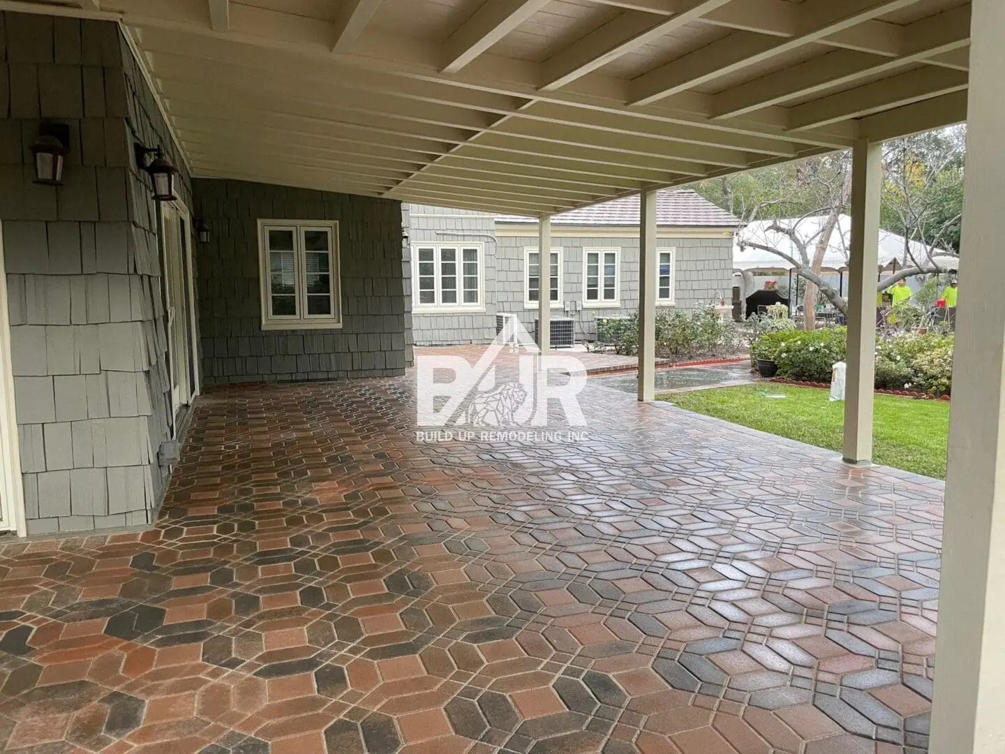 Spacious covered patio with patterned tile flooring and white pillars.