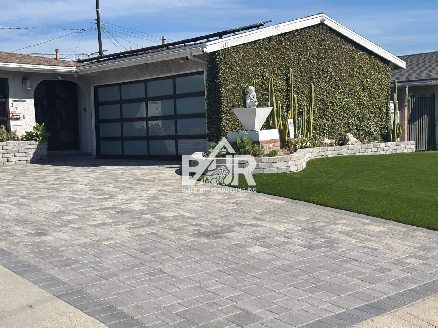 Modern house with a spacious driveway and green ivy on the wall.