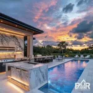 Luxury outdoor kitchen and pool at sunset.