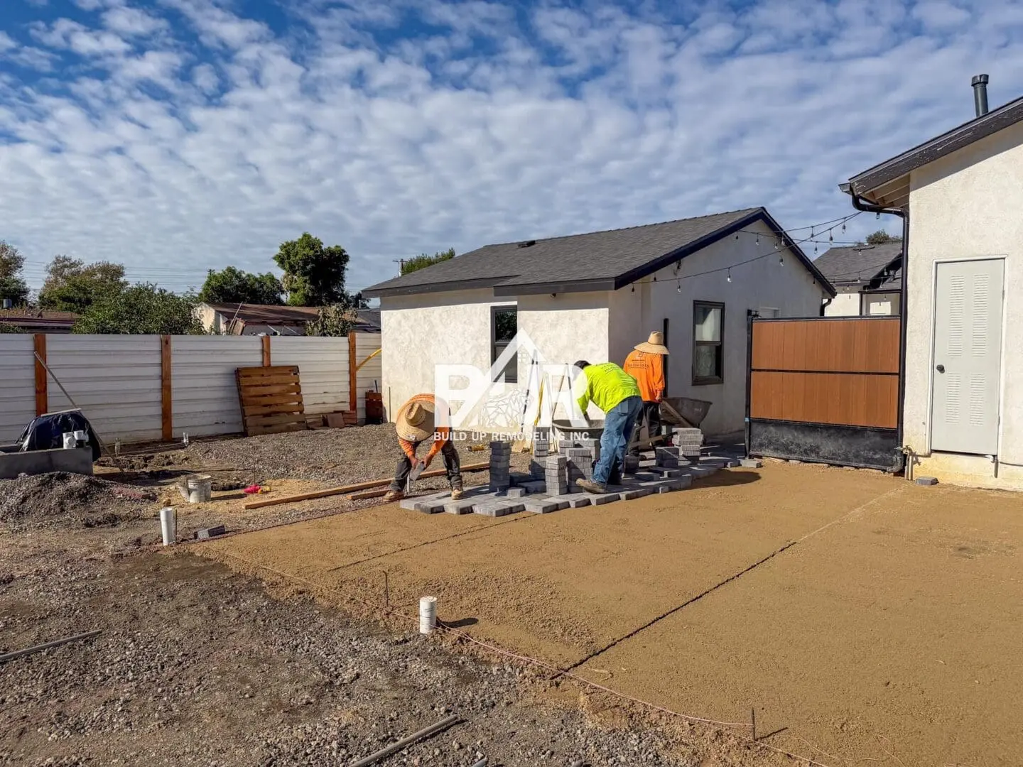 Workers laying pavers in a backyard.