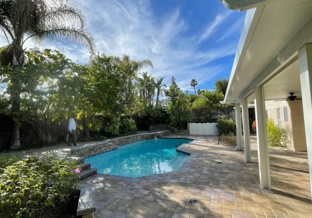 Backyard pool with patio and trees.
