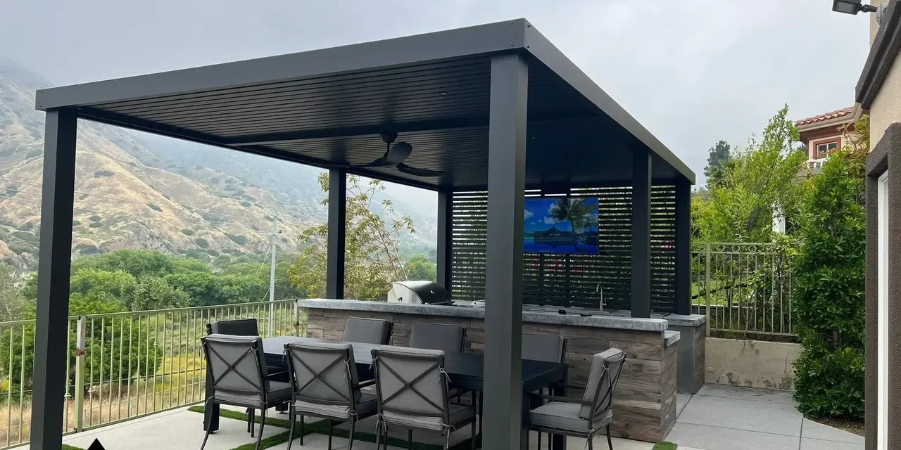 Modern outdoor kitchen with bar seating under a pergola.